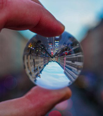 Kırpılmış el, binaların yansıması olan küçük bir kristal küreyi tutuyor.