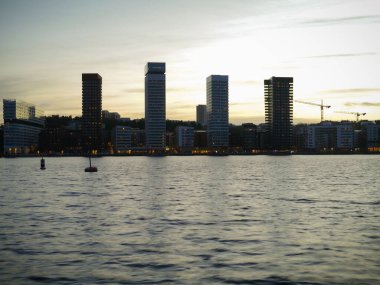 Gün batımında gökyüzüne karşı binaların nehir manzarası