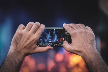 Konser sırasında cep telefonuyla çekim yapan bir adam. 