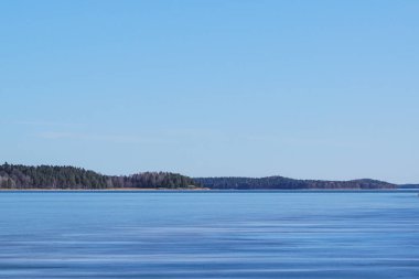 Açık mavi gökyüzüne karşı bir gölün manzarası