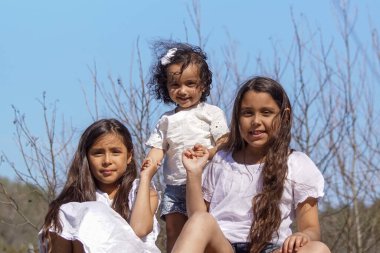 Portrait of sisters on field in against blue sky 