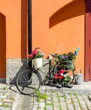 a bicycle decorated with flowers by the house wall