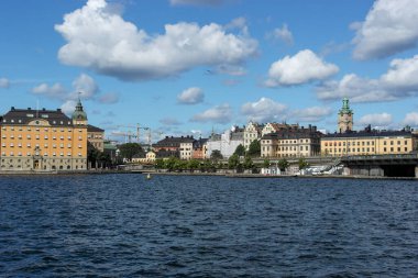 Bulutlu gökyüzüne karşı nehir kıyısındaki binaların görüntüsü