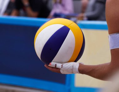 Cropped hand of person holding ball while playing beach volleyball