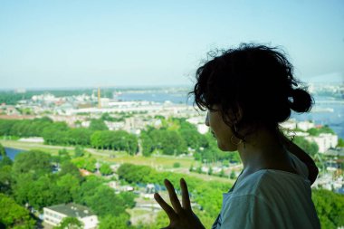 Side view of woman looking at cityscape against sky