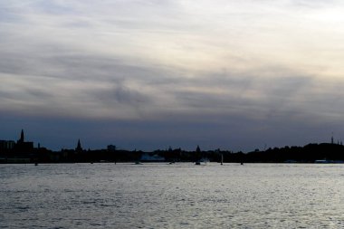 Silhouette buildings by sea against sky