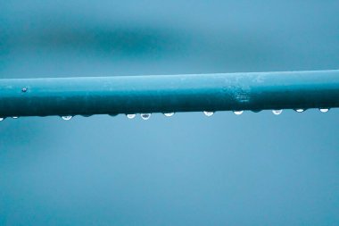 Close up of water drops on blue metal pipe 