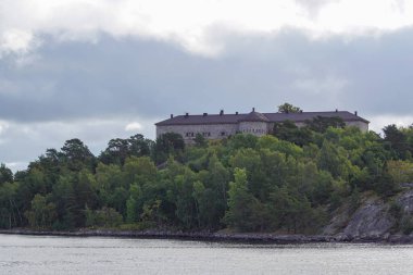 Gökyüzüne karşı bir adada eski bir taş bina 