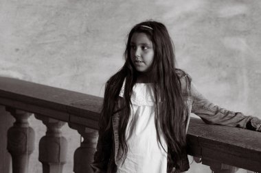 Cute girl looking away while standing against stone fence 