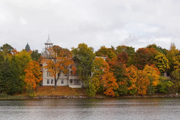 Trees and building by lake against sky during autumn