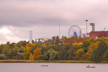 amusement park next to lake against sky during autumn