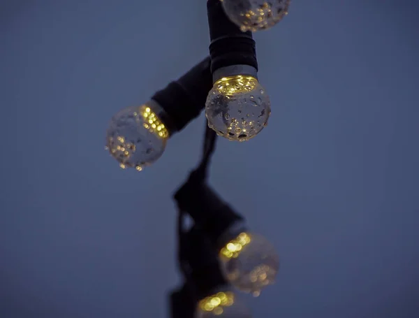 Low angle view of illuminated light bulbs against clear sky