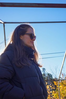 Gökyüzüne karşı güneş gözlüğü takan bir kadın.