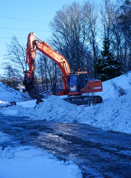 View of a excavator standing on snow covered field against sky
