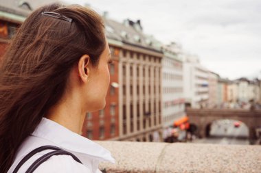 Kentteki binalara karşı duran genç bir kadının yan görüntüsü