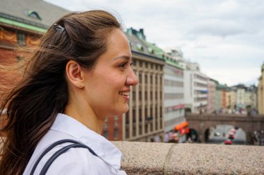 Binalara bakan gülümseyen genç bir kadının yan görüntüsü