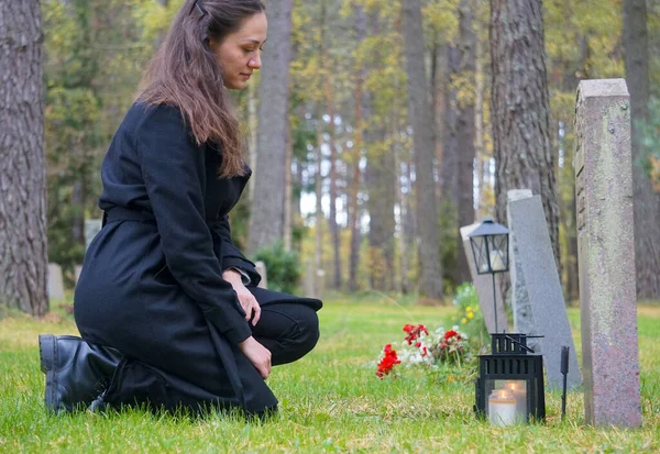 Side view of woman crouching next to gravestone