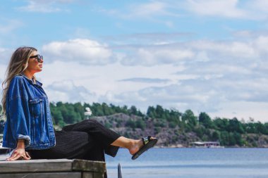 Takımadalarda iskelede oturan kadının yan görüntüsü 