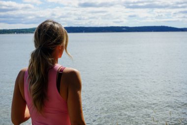 Gökyüzüne karşı denize bakan kadının dikiz görüntüsü