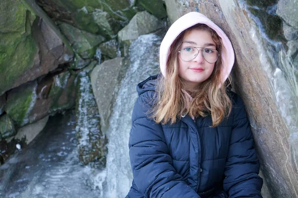 Dağ duvarında oturan genç kızın portresi 