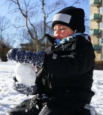 Binanın önünde karla oynayan bir kızın görüntüsü 