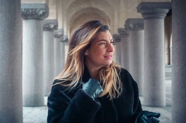 Sütunların arasında duran genç bir kadının profili