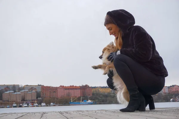 Köpeğiyle sokakta çömelmiş bir kadın.