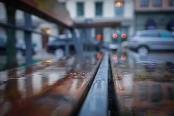 Close up of a wet wooden park bench in the city