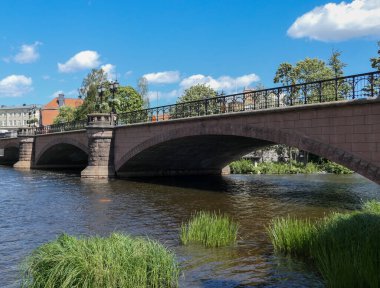 Nehir üzerindeki kemer köprüsünün alçak açılı görüntüsü gökyüzüne karşı