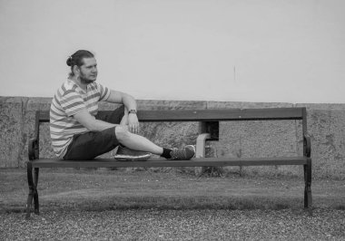 Binanın önündeki bankta oturan bir adam. 