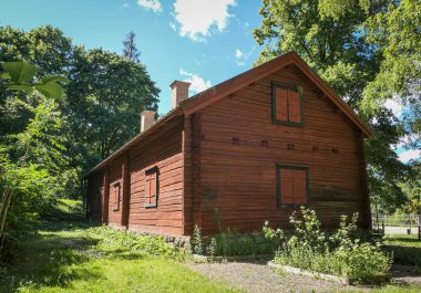 Ağaçlar ve gökyüzüne karşı geleneksel kırmızı bir ahşap bina. 
