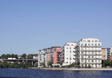 View of buildings by river against clear blue sky