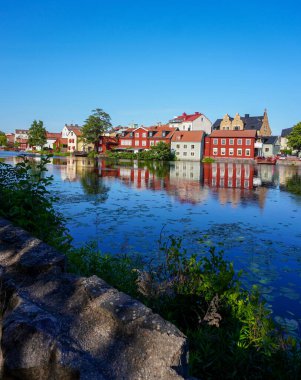 Açık mavi gökyüzüne karşı binaların yanındaki göl manzarası