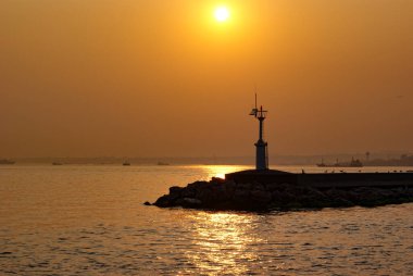 Gün batımında deniz kenarındaki siluet deniz feneri
