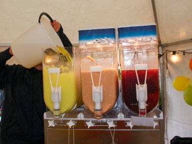 Tanınmayan biri buzlu içecek makinelerini doldurur.