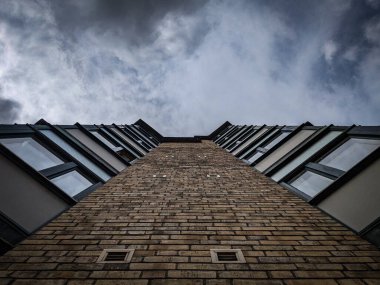 Bulutlu gökyüzüne karşı tuğla bir binanın alçak açılı görüntüsü 