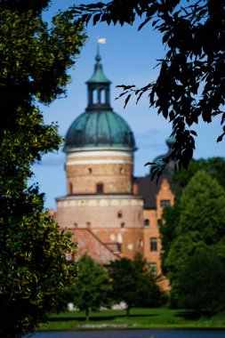 Ağaçların arasından görünen eski bir bina. 