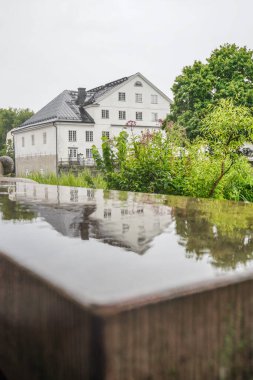 Islak taş bir bankta bir binanın yansıması. 