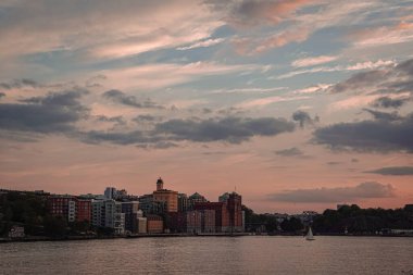 Gün batımında gökyüzüne karşı binaların deniz manzarası