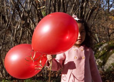 Önünde balon tutan bir kız. 