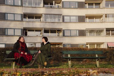 Binanın önünde iki kişi oturuyor. 