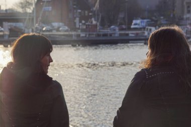 Nehrin kenarında iki kadın oturuyor. 