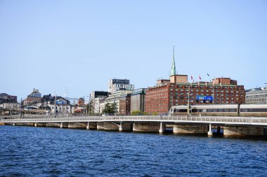 View of buildings by river against clear blue sky