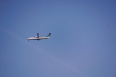 Açık mavi gökyüzüne karşı uçan bir uçak