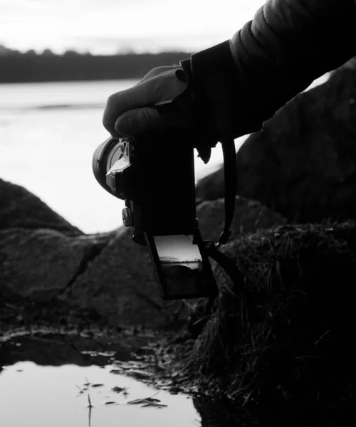 Cropped hand holding a camera at a lake