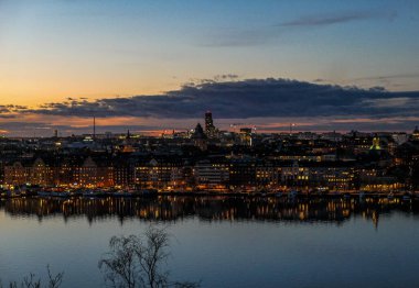 Gün batımında gökyüzüne karşı nehirden aydınlatılmış binaların yüksek açılı görüntüsü
