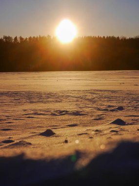 Gün batımında karla kaplı bir tarla 