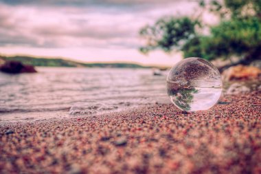 Kumsalda gökyüzüne karşı kumdaki kristal küreye yakın çekim