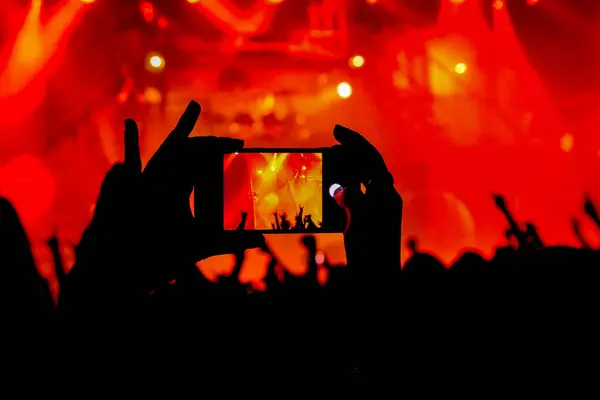 Konserde cep telefonuyla fotoğraf çeken biri. 