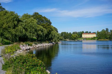 Scenic view of a lake against blue sky in Sollentuna  clipart